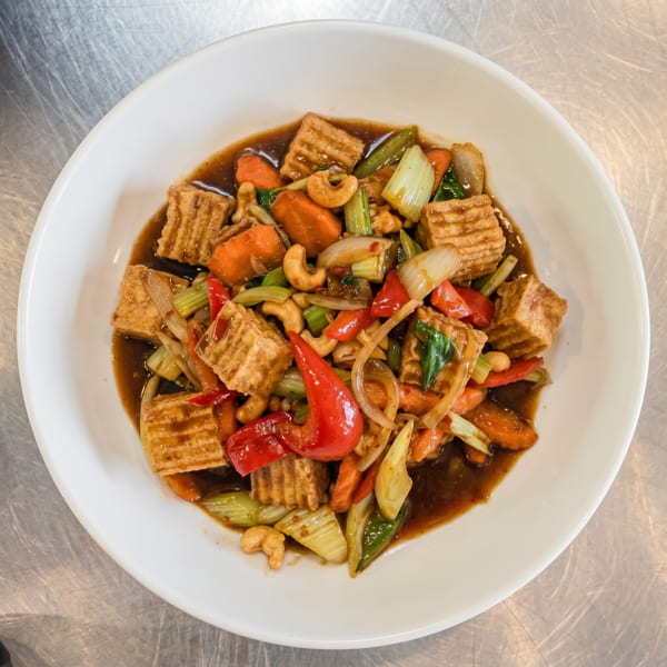 Tofu stir-fry with cashews, red peppers, carrots, celery, and onions in a rich brown sauce.